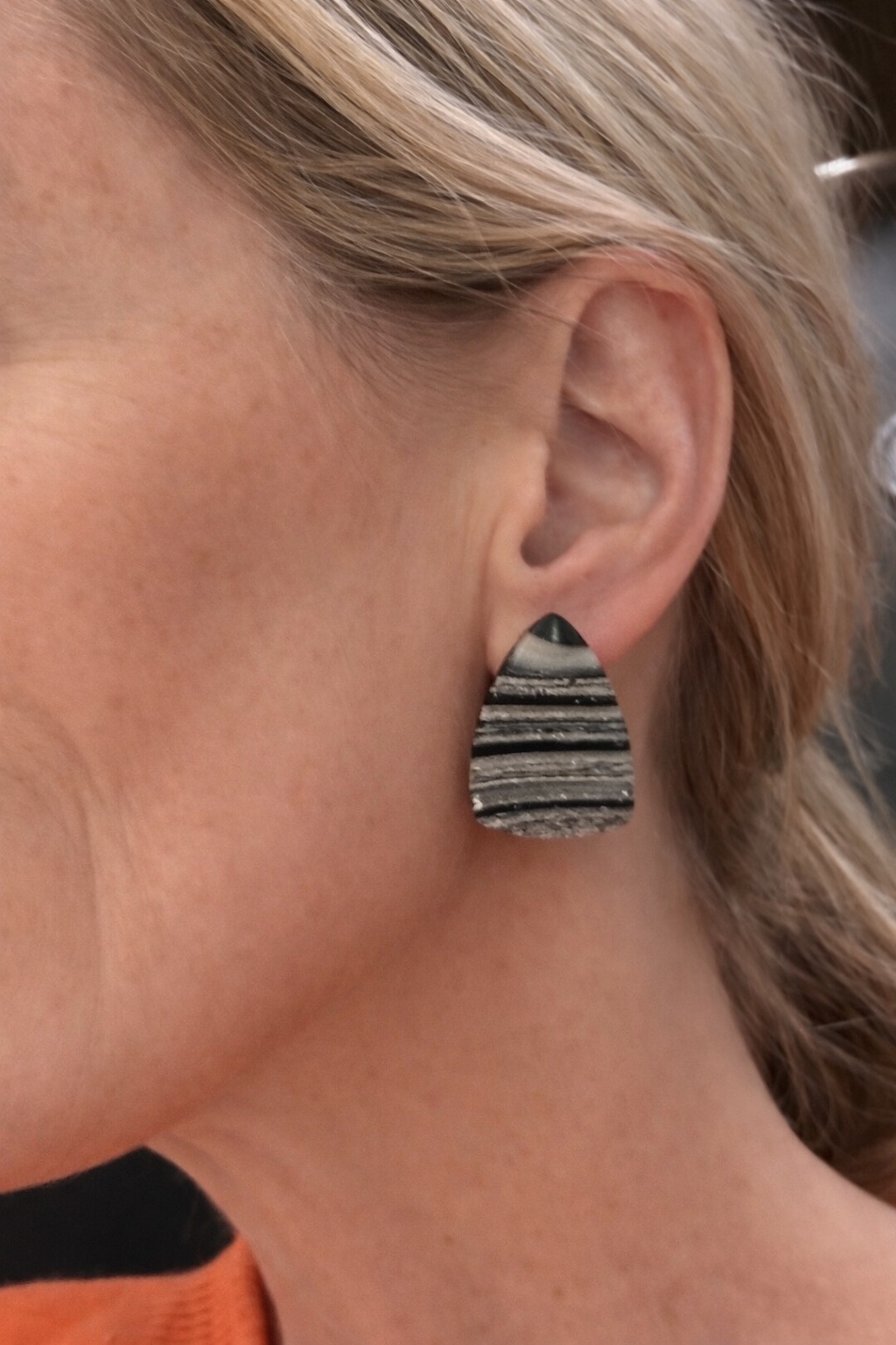 Close-up of a black and pale striped earring worn at the ear